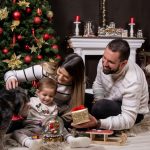 A joyful moment with family by the Christmas tree, gifting and playing with a dog.