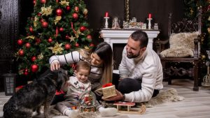 A joyful moment with family by the Christmas tree, gifting and playing with a dog.
